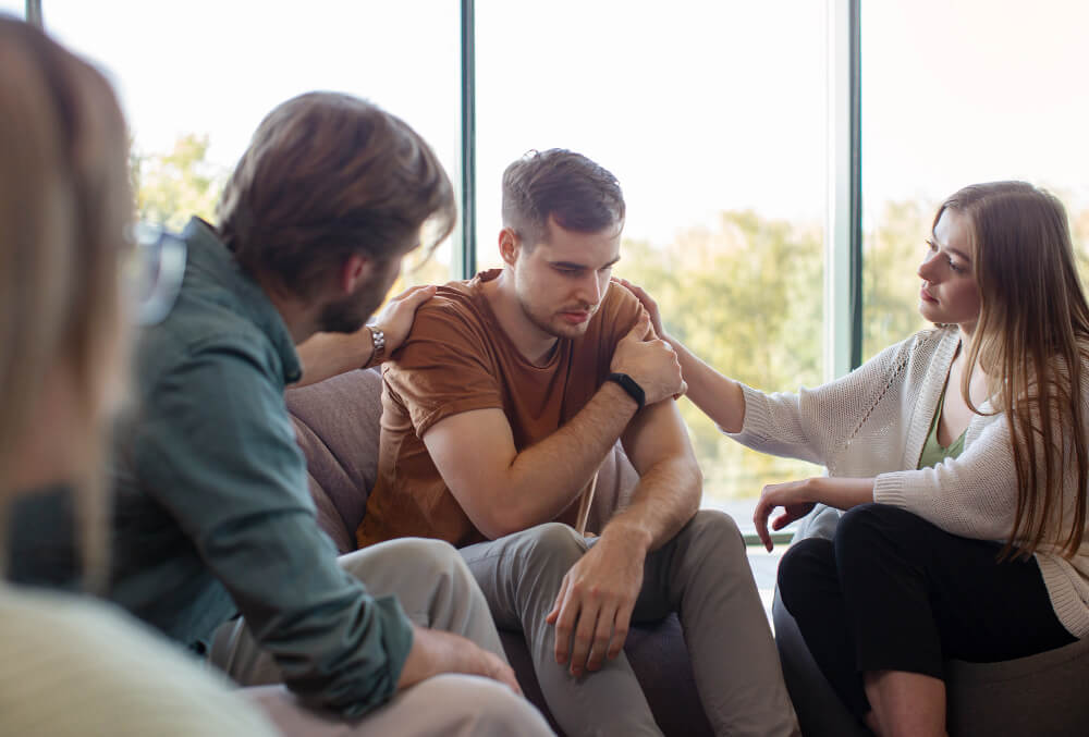 Support group consoling a member after sharing his experience. 
